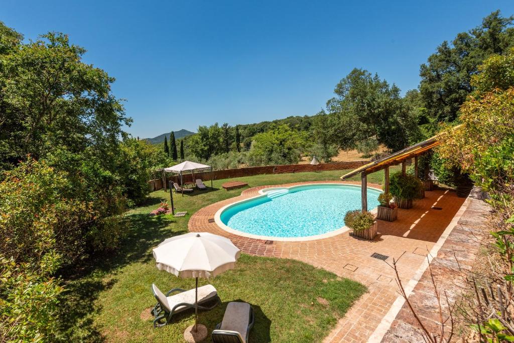 an outdoor swimming pool with an umbrella and chairs at Agriturismo Podere Marroneto in Monticiano