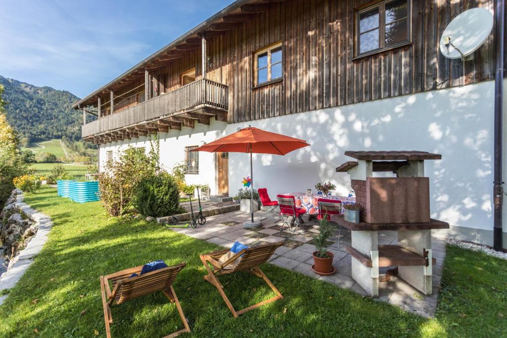 a patio with a grill and two chairs and an umbrella at Alpen Chalet Alte Talstation in Lenggries