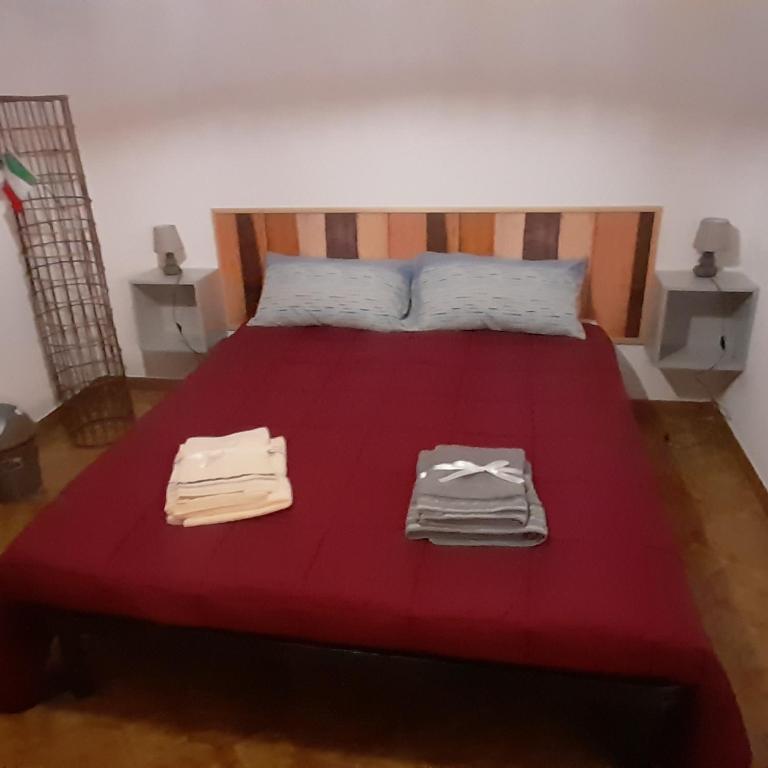 a bedroom with a red bed with towels on it at B e B Beglia Alguer in Alghero