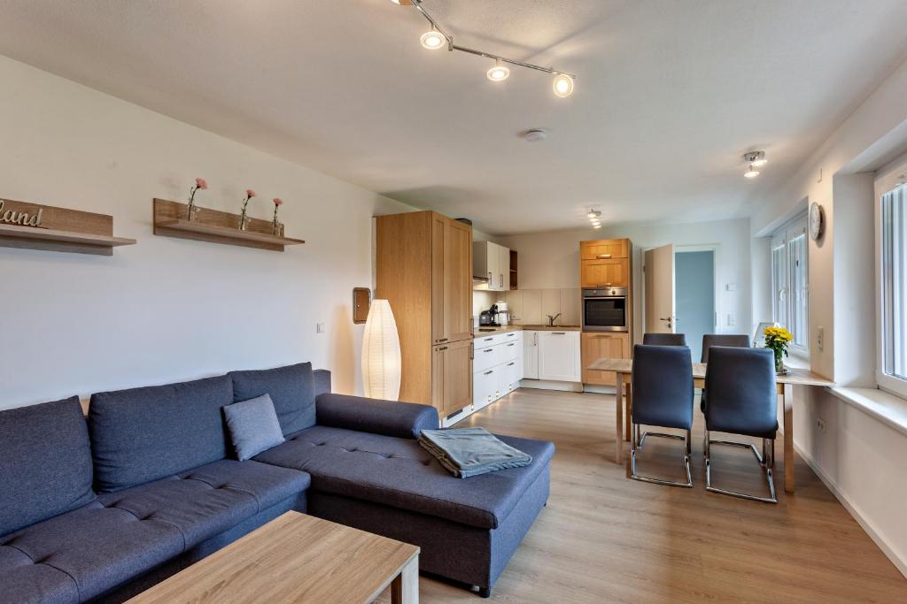 a living room with a blue couch and a kitchen at Ferienwohnung Kleine Auszeit in Schmallenberg