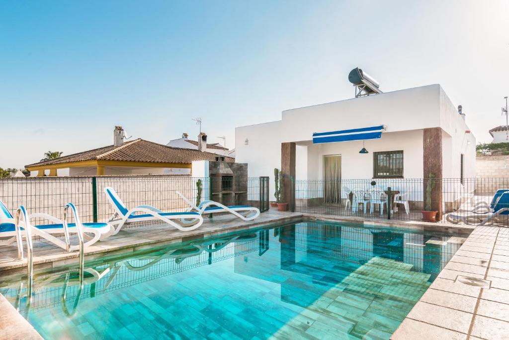 a swimming pool with chairs and a house at Chalet Rubio Cabeza in Conil de la Frontera