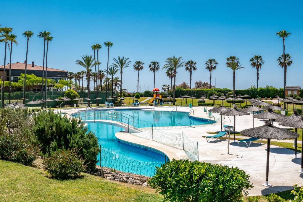 a pool at a resort with palm trees at Kiko Las Americas in Isla Cristina