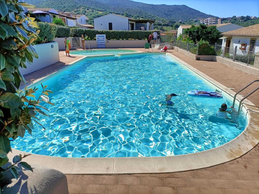 a large blue swimming pool with people in it at Villa Vigna in Badesi