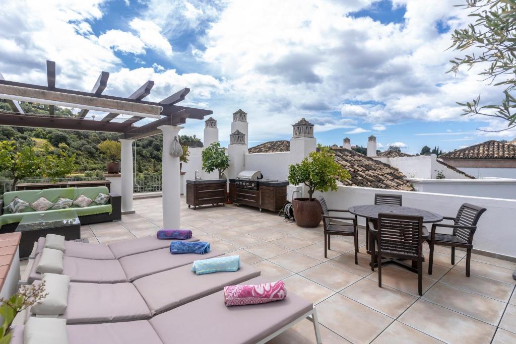 an outdoor patio with a table and chairs and a pergola at Beautiful penthouse with solarium in Benahavís