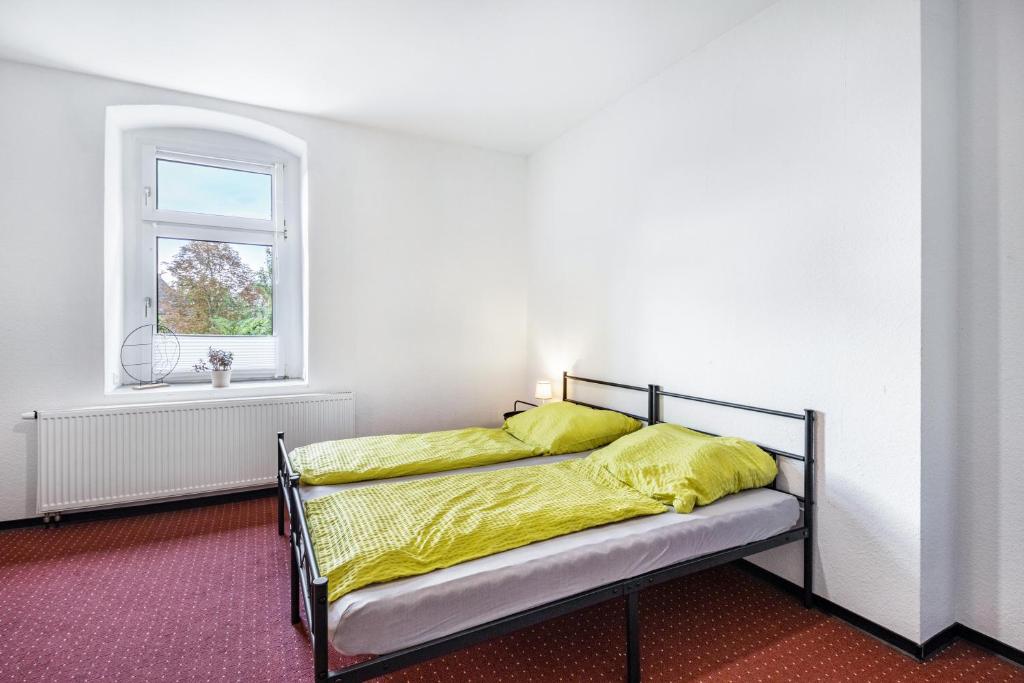 a bed with yellow sheets in a room with a window at Haus Wipperblick in Osmarsleben