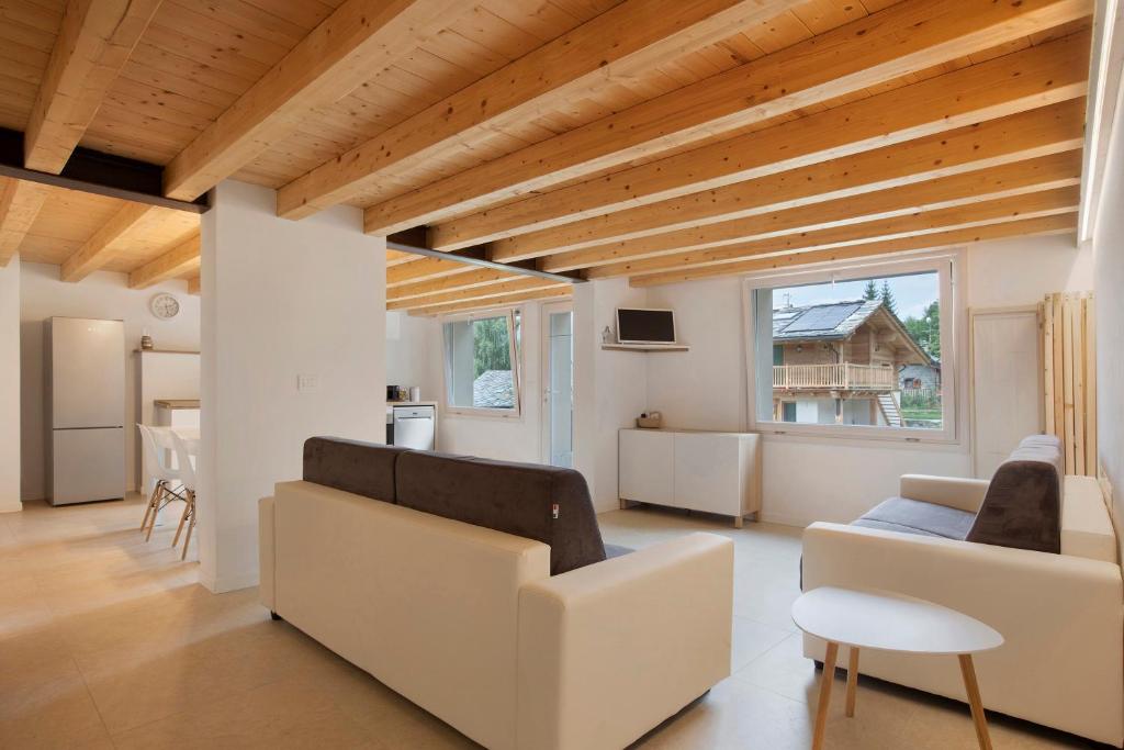 a living room with white furniture and a wooden ceiling at Maison Millet Ozein in Aymavilles