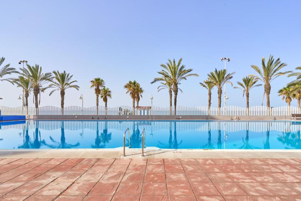 a swimming pool with palm trees in the background at Playa Algarrobo Costa in Algarrobo-Costa