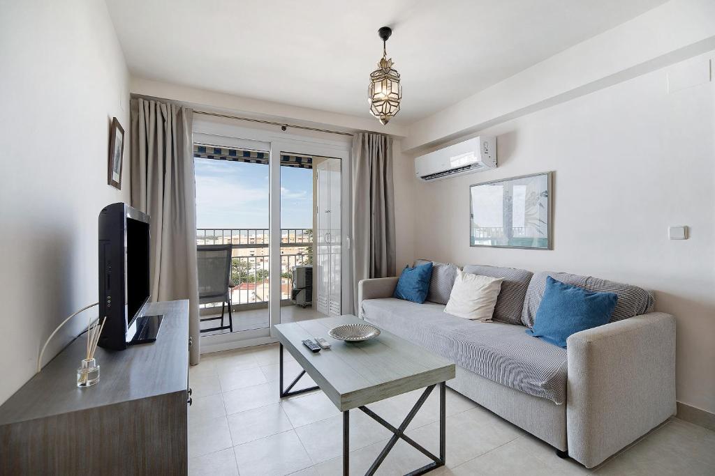 a living room with a couch and a tv at Doña Amparo chipiona Playa de Regla in Chipiona