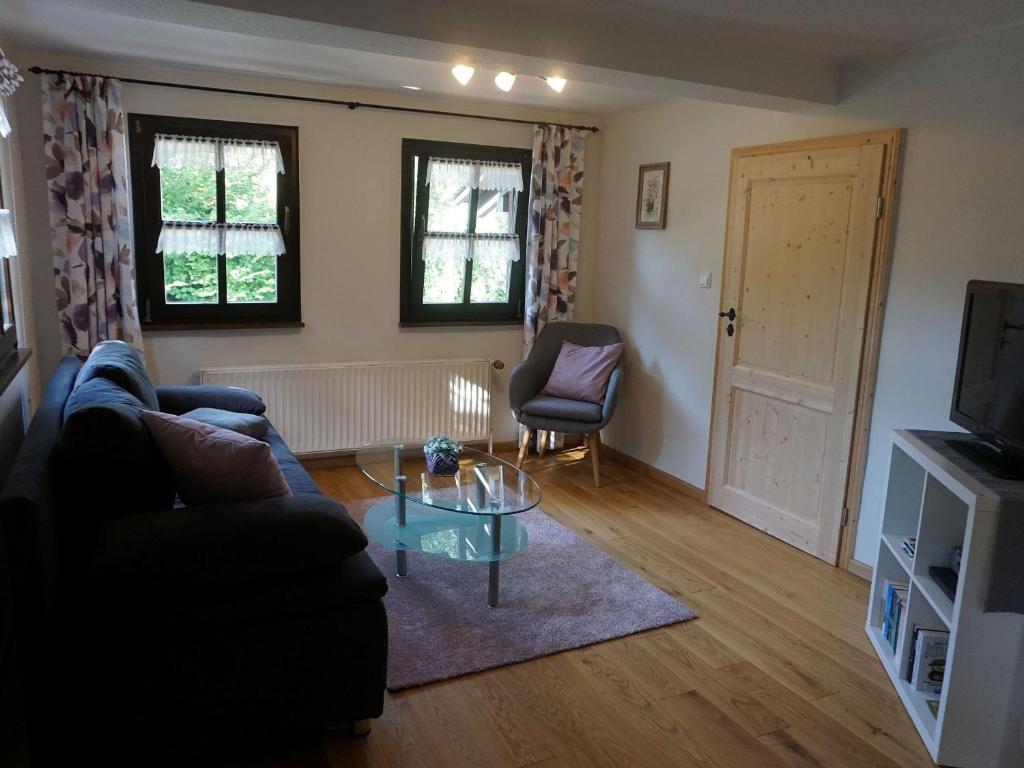 a living room with a couch and a glass table at Ferienhaus am Leiselbach in Leisel