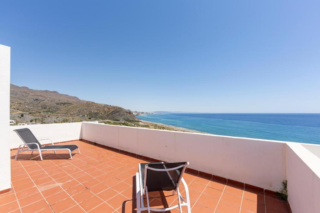 two chairs sitting on a balcony overlooking the ocean at Duplex jlc in Mojácar