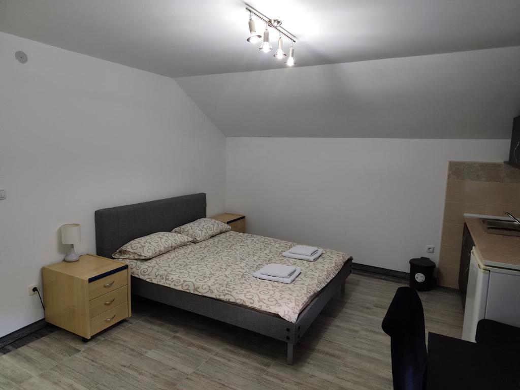 a small bedroom with a bed and a night stand at Apartmani Gradac in Valjevo