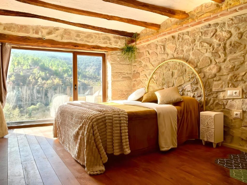 a bedroom with a bed with a stone wall at Duende in Olba