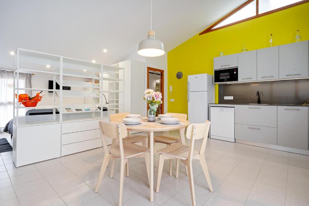 a kitchen with a table and chairs and a yellow wall at Loft El Til-ler in Bellvei del Penedes