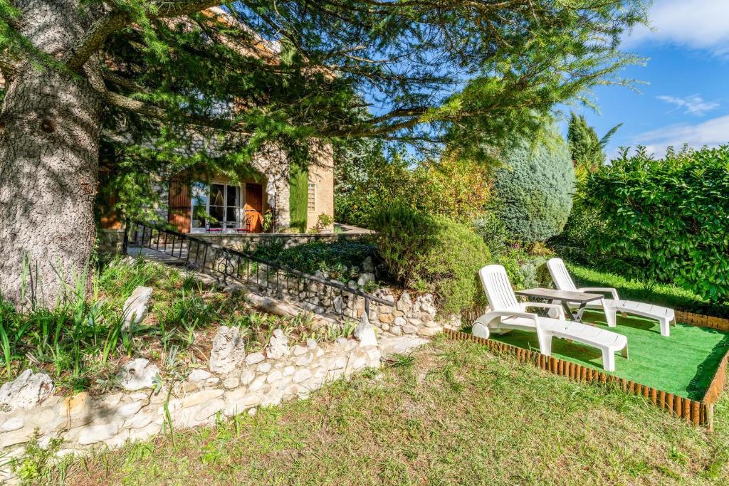 a garden with two white chairs and a tree at Gîte Le Séguret in Entrechaux