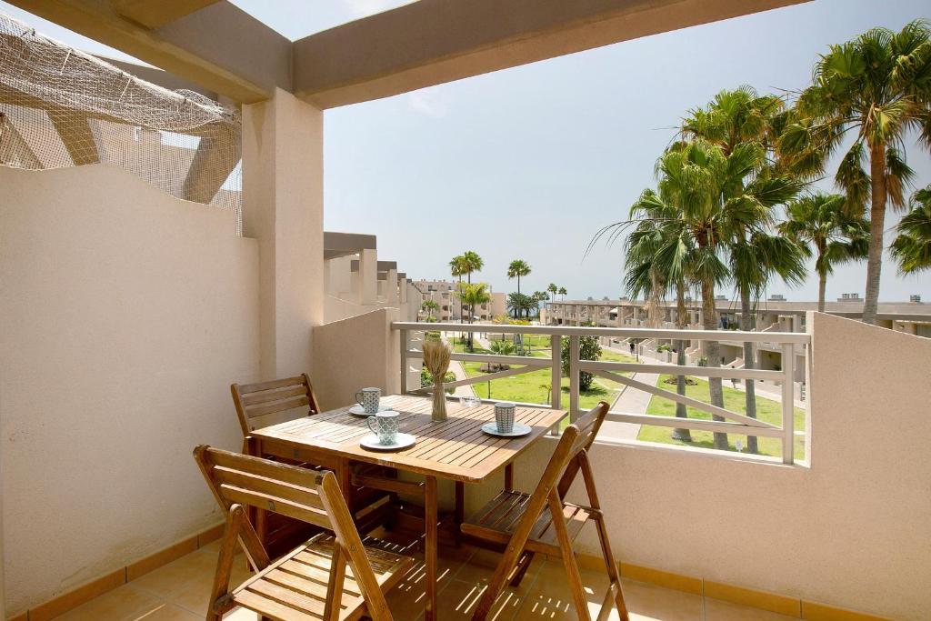 a table and chairs on a balcony with palm trees at Costa Bella la Tejita in La Tejita