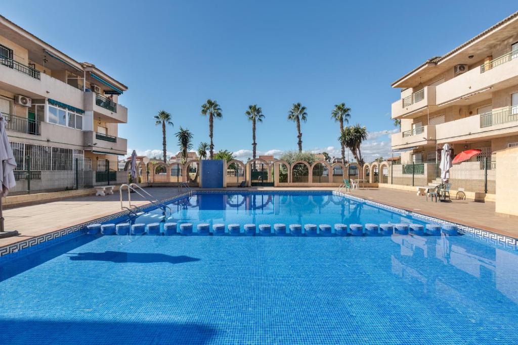 a large swimming pool with palm trees and buildings at Casa Pepe in Los Narejos