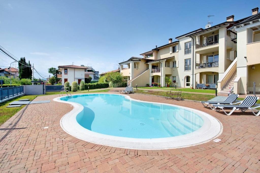 a swimming pool with two chairs and a building at Everlakegarda in Desenzano del Garda