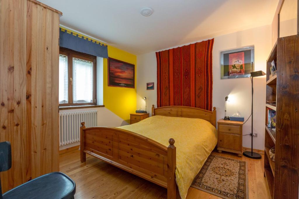 a bedroom with a wooden bed and a window at Chambre d'hôtes dans les Alpes in Conclonaz