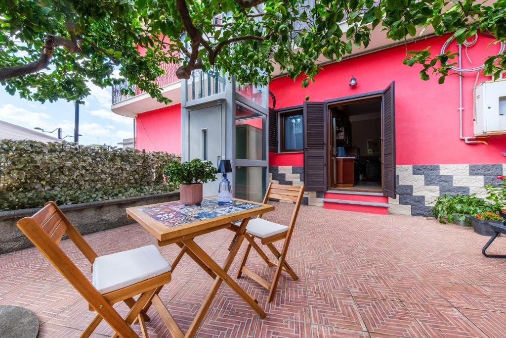a table and chairs in front of a pink building at La Casa dei Limoni in Gaggi