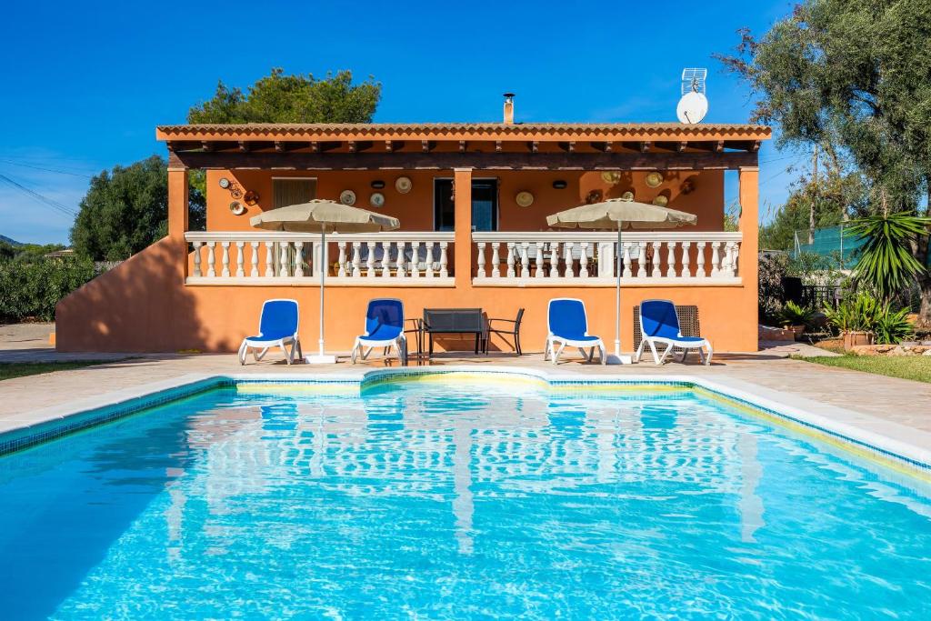 a villa with a swimming pool with chairs and a house at Can Pota in Portocolom