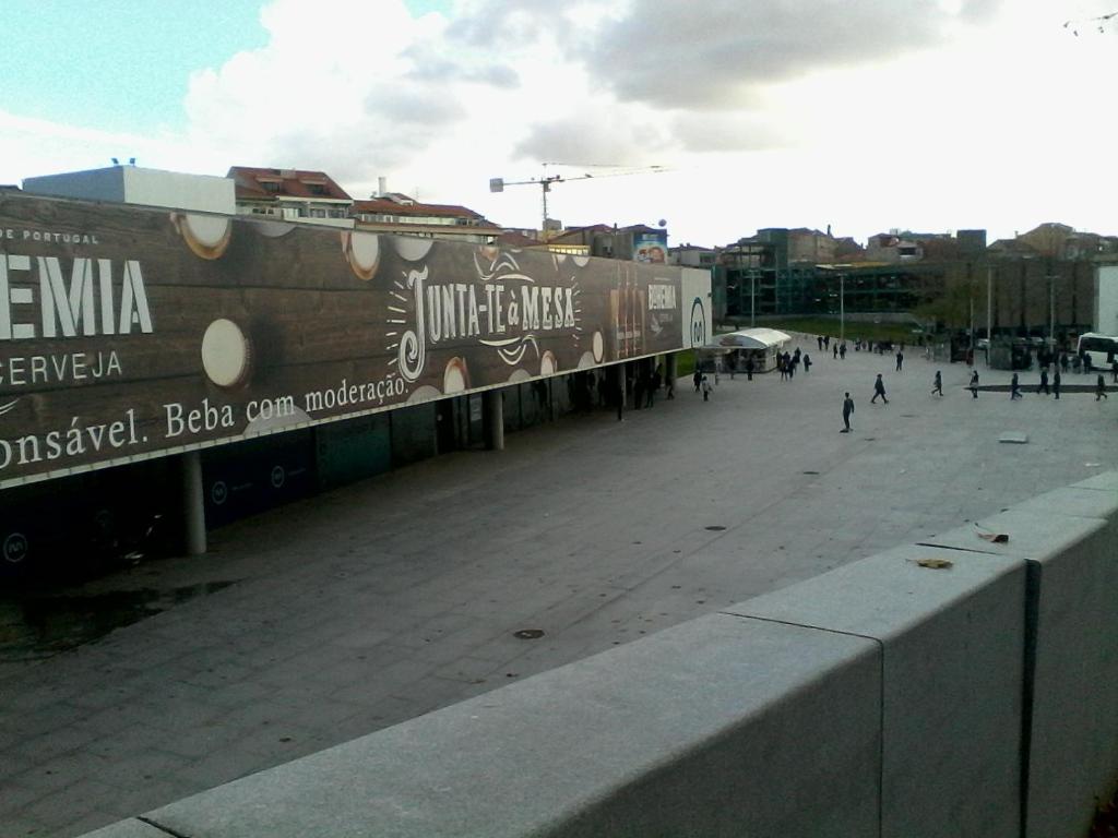 a train on a track with people walking on a street at Metro-Apartment RNAL nº35375 AL-Chamada para a rede móvel nacional in Porto