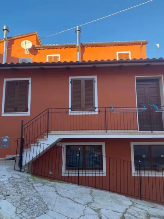 a red building with a staircase and a balcony at Il Focolare dei Sibillini in Visso