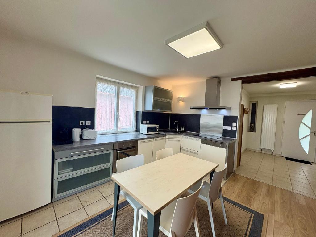 a kitchen with a table and a white refrigerator at Maison Des 3 Vallées - Wifi Véranda in Montmélian