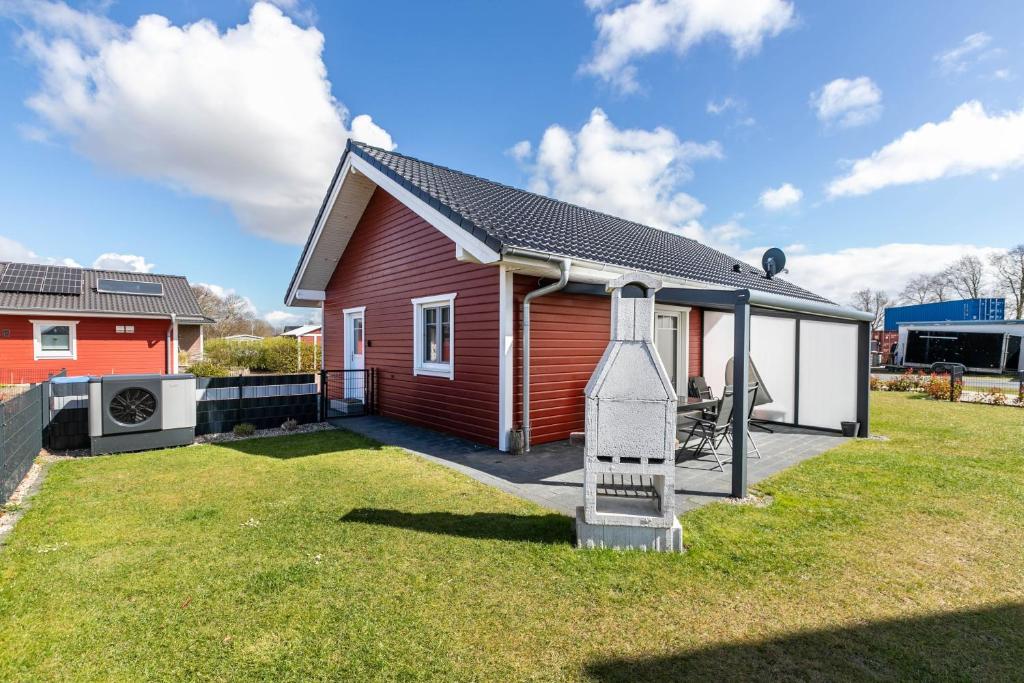 a red house with a ladder in the yard at Ferienhus-voern-Diek in Kaiser Wilhelm Koog