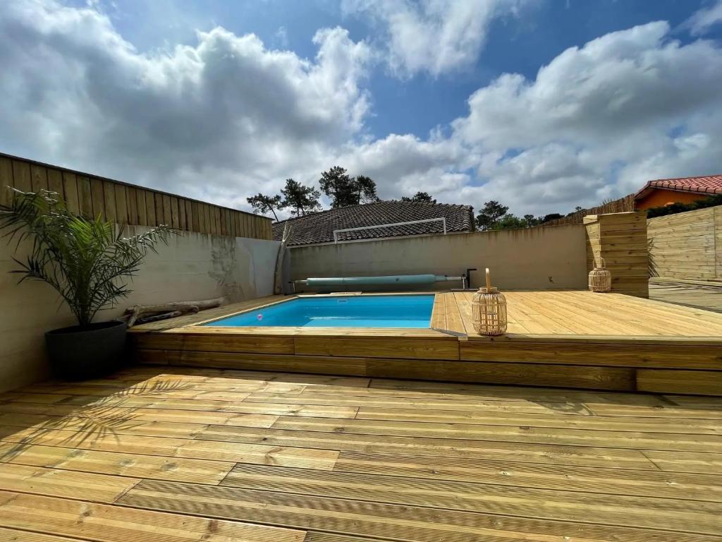 a swimming pool in a backyard with a wooden deck at Maison Cosy avec Piscine in Tarnos