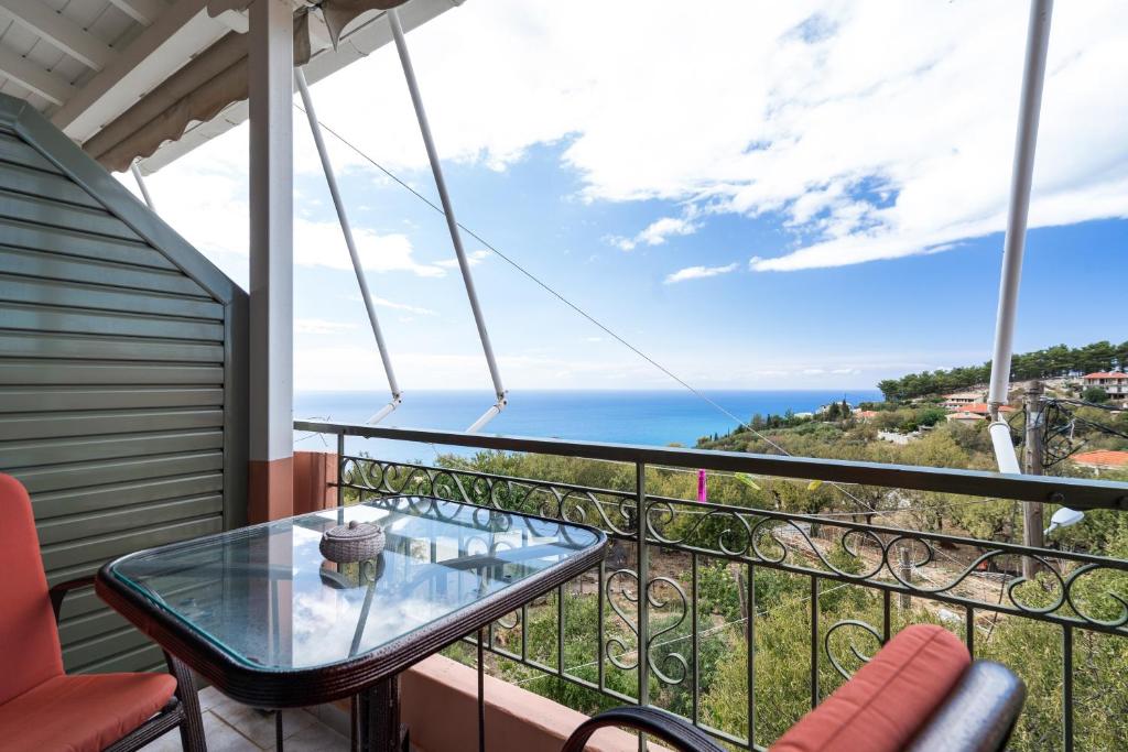 a balcony with a glass table and a view of the ocean at Nontas Home 33 in Kalamitsi