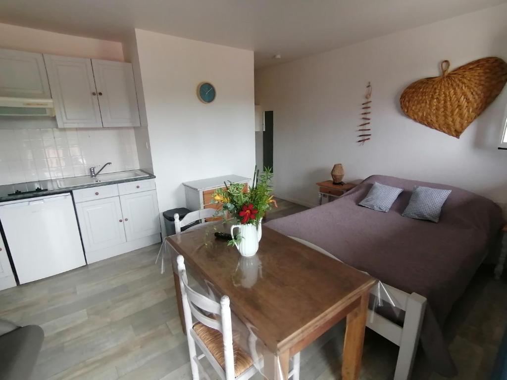 a room with a bed and a table and a kitchen at Les Alisiers in Eugénie-les-Bains