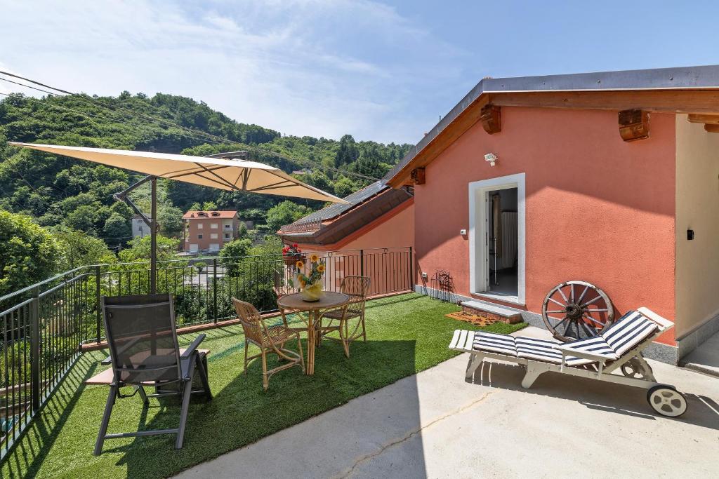 a patio with a table and chairs and an umbrella at Maison Nature e Relax Rubino in Osiglia