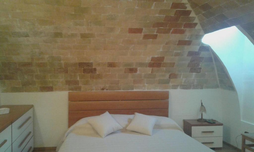 マテーラにあるPortico dei Sassiのレンガの壁、ベッド付きのベッドルーム1室