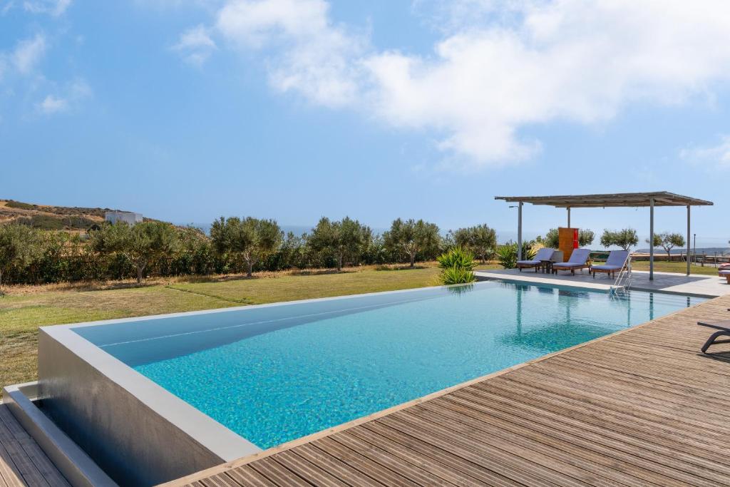 a swimming pool with a wooden deck next to a house at Luna Rossa Milos - Cocoon in Provatas