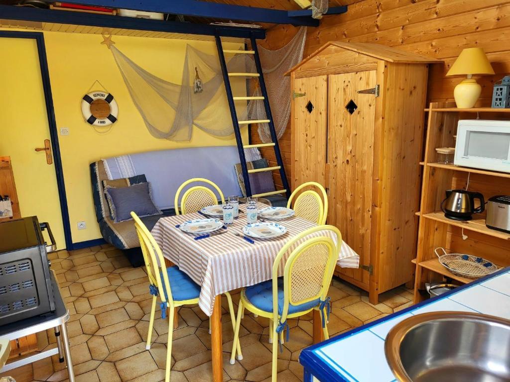 a dining room with a table and chairs and a ladder at Maison De Plage La Grise Brèche in Pirou