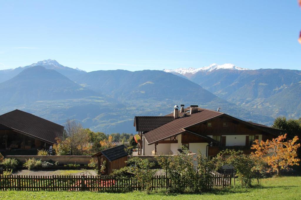 a house with a fence and mountains in the background at Eichernhof Apartment Kirschblüte in Verano
