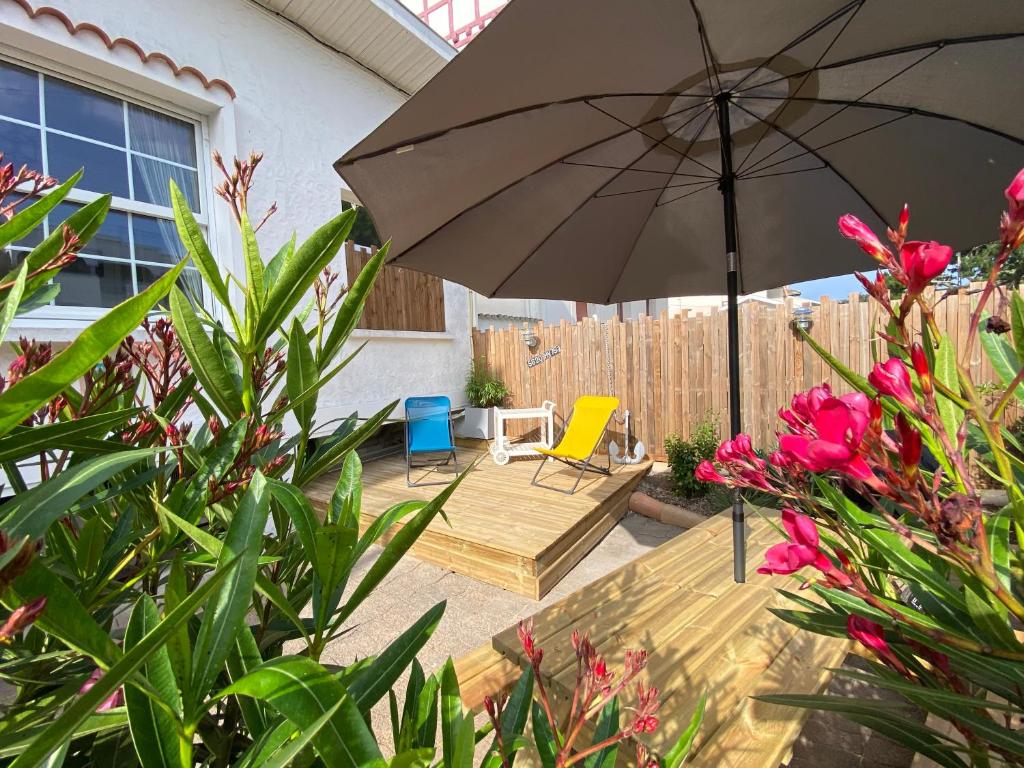 a patio with an umbrella and chairs and flowers at Appartement bord de plage-Arcachon in Arcachon