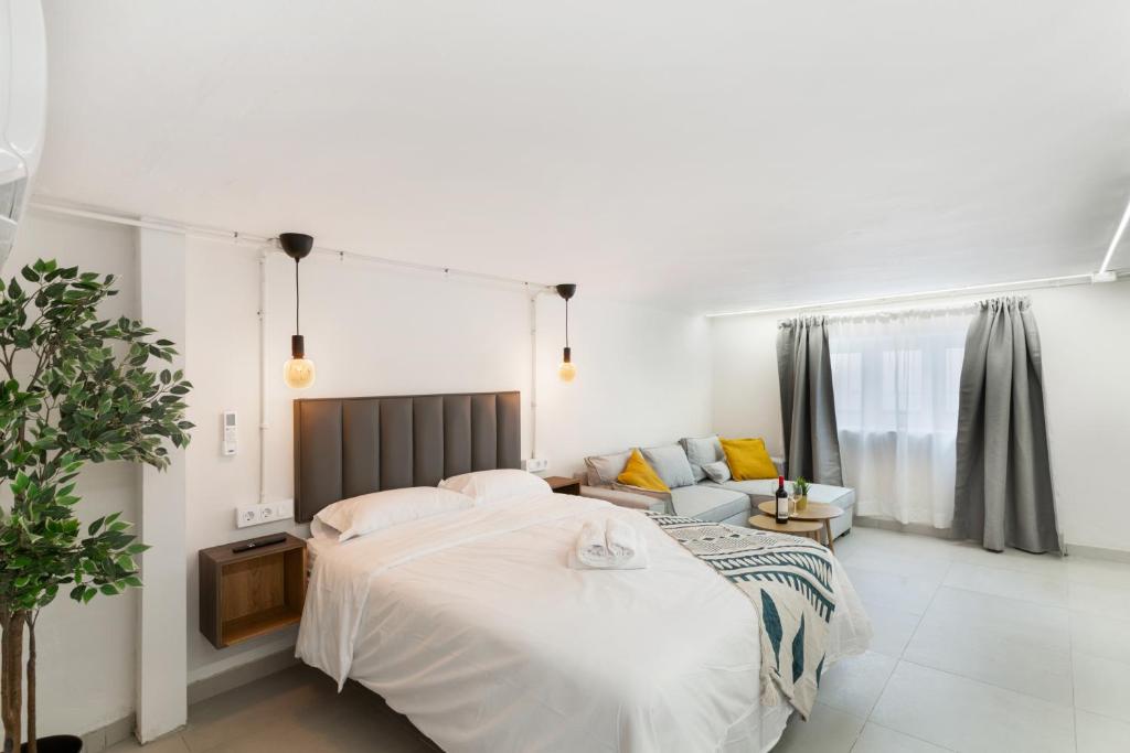 a white bedroom with a bed and a couch at Atw Studio in Guanarteme