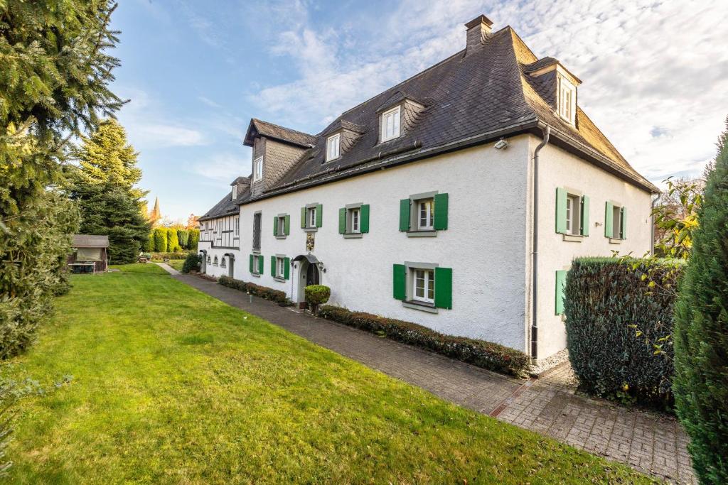 an exterior view of a white house with green shutters at Appartment Schlossmühle in Olsberg in Olsberg