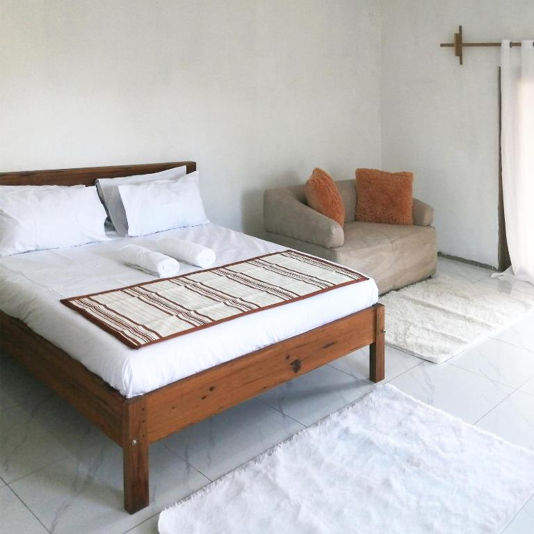 a bed in a living room with a couch at Duna Serena Tiny Houses in Praia do Tofo