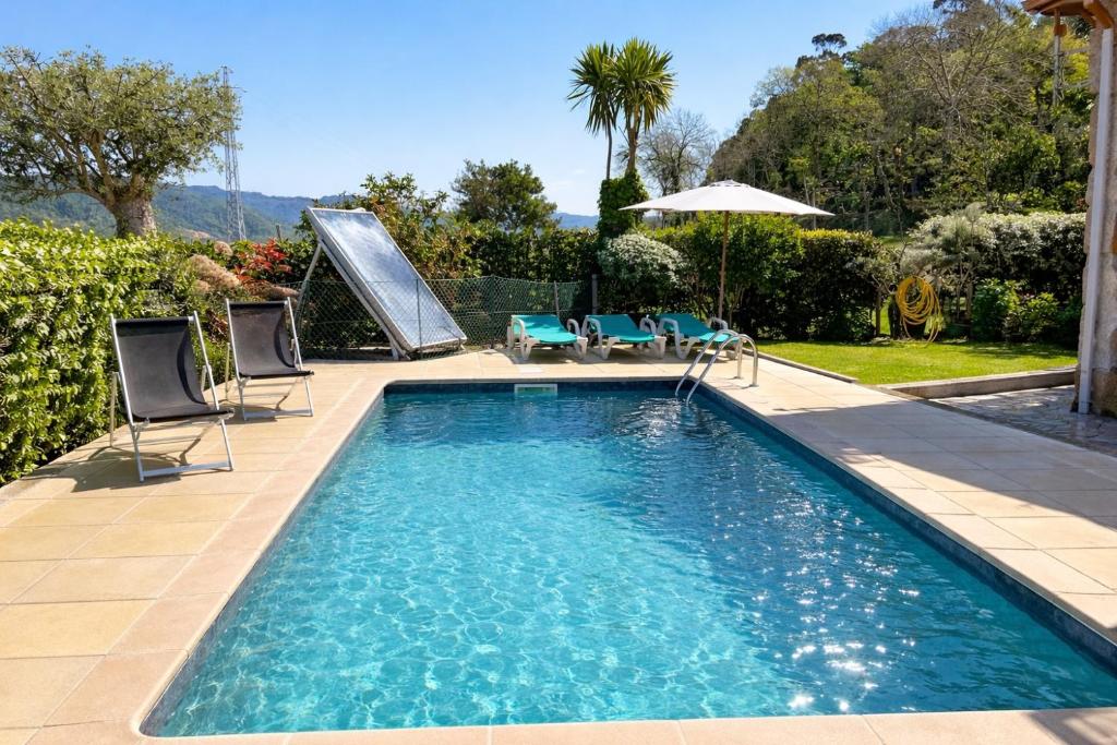 a swimming pool with chairs and an umbrella at Casa da Lage - Piscina privada - Vistas rio - "Gerês" in Geres