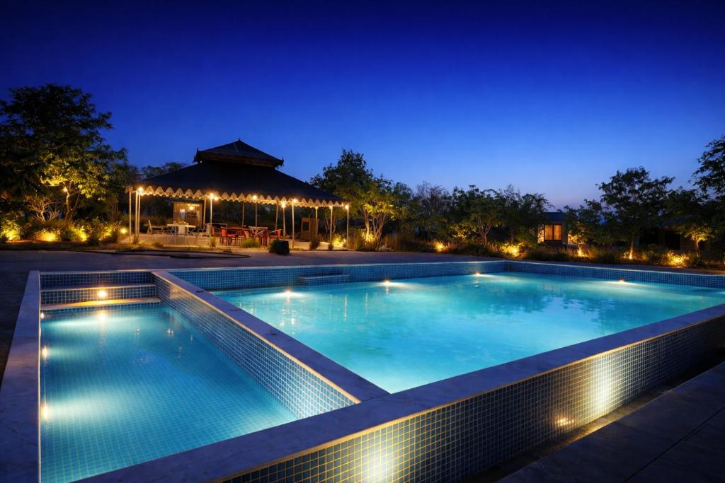 a swimming pool at night with a gazebo at Jawai Leopard Safari Lodge in Bera
