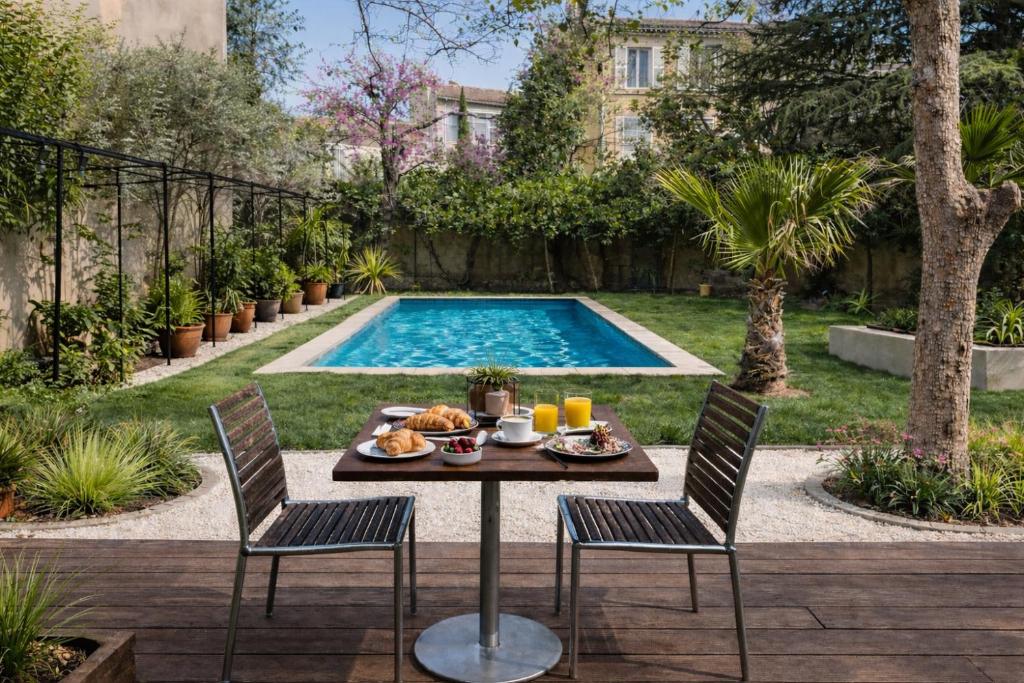 a table and chairs in front of a swimming pool at Les Chambres Salonaises in Salon-de-Provence