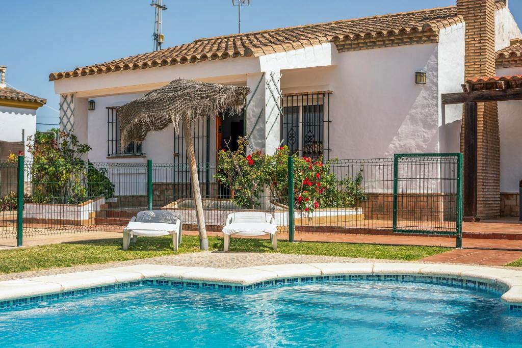 a swimming pool with two chairs and an umbrella at Chalet Villa Ariza in Cádiz