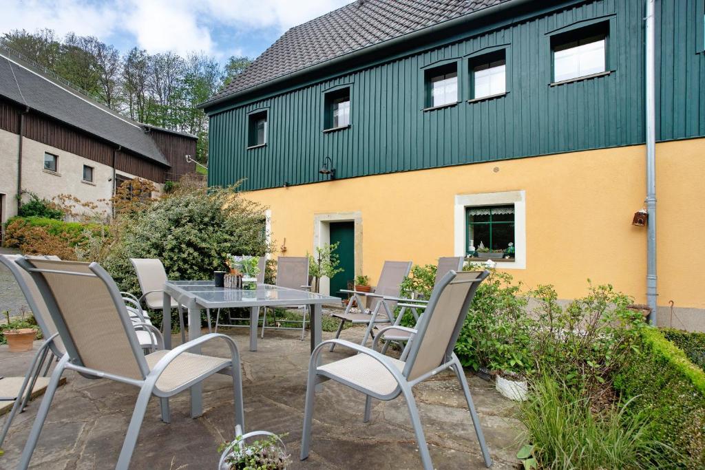 a patio with a table and chairs in front of a building at Ferienwohnungen 'am Waldrand' in Bad Gottleuba