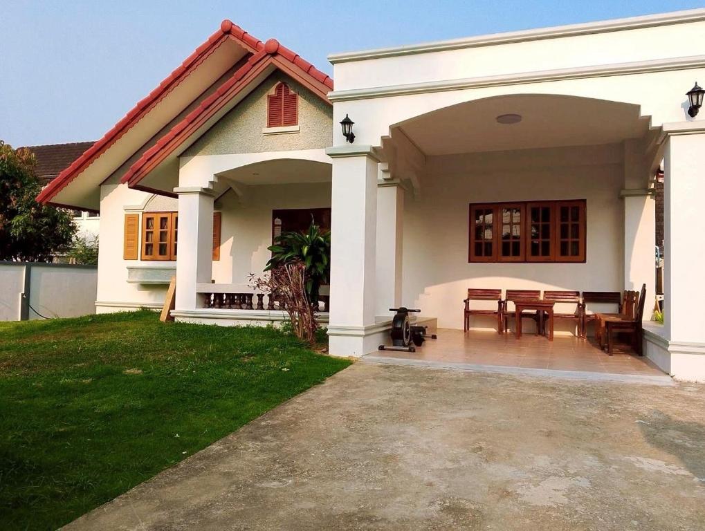 a white house with a table in the backyard at บ้านกรรณิการ์ in Chiang Mai