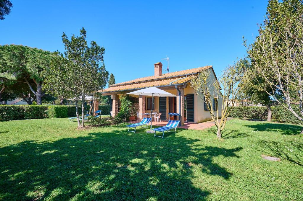 a small house with a table and chairs in a yard at Mare Etrusco Villetta D2 in Populonia