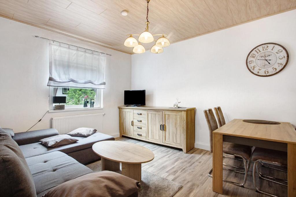 a living room with a couch and a table and a clock at Fewo In Schustes in Willingen