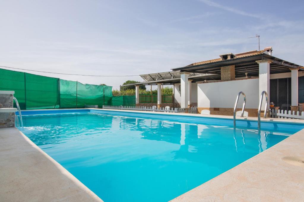 a swimming pool with blue water in front of a house at Finca El Abuelo in Lepe