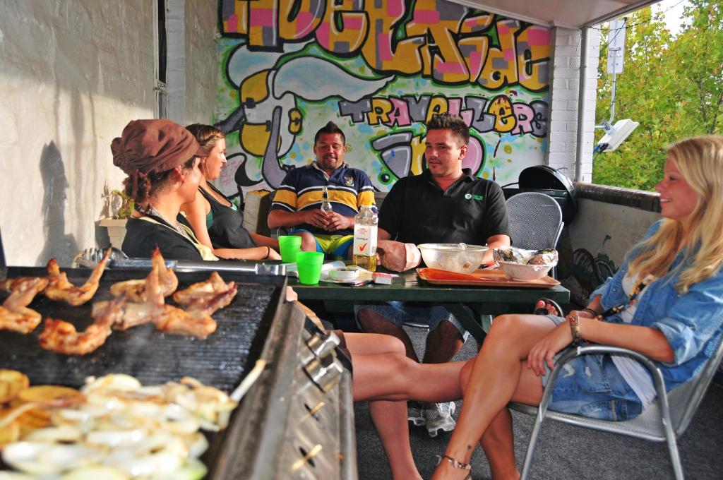 a group of people sitting at a table near a grill at Adelaide Travellers Inn Backpackers Hostel in Adelaide